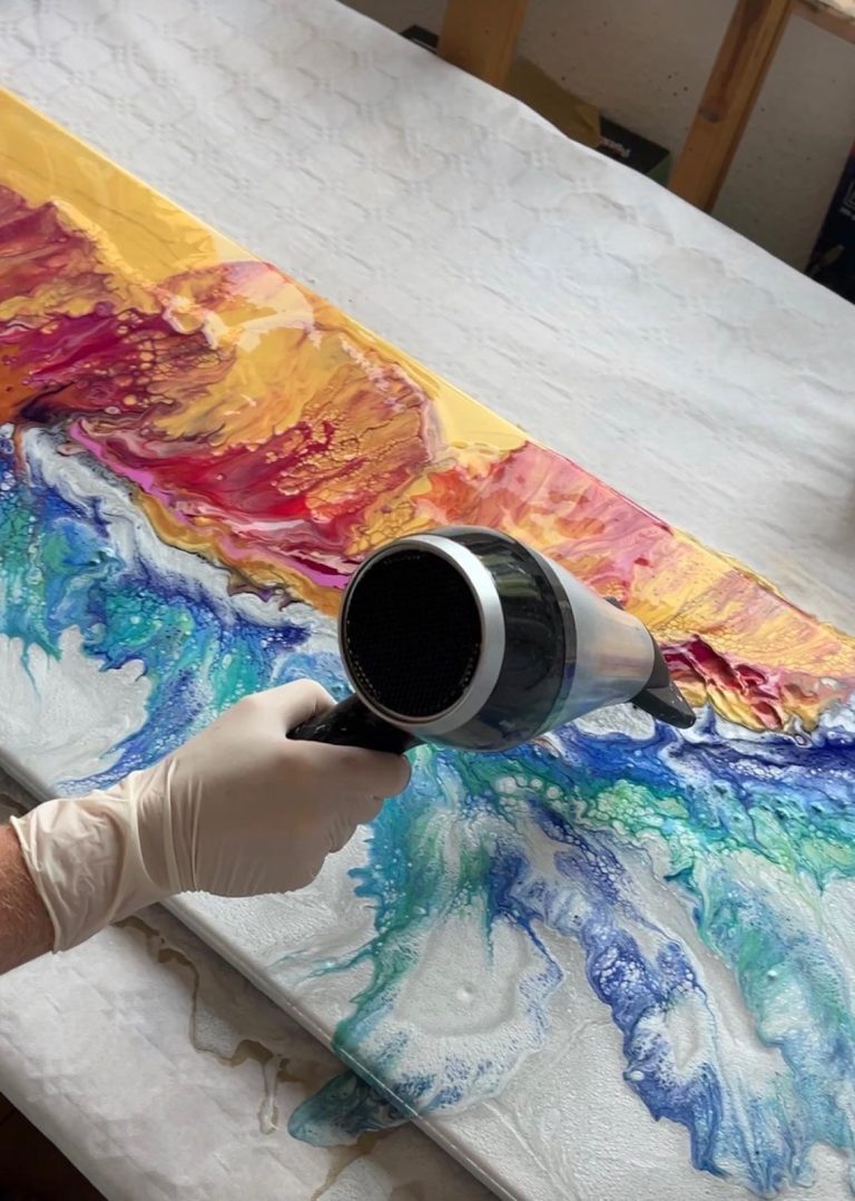 Haartrockner in Aktion, der bunte Farben auf einer Leinwand vermischt.