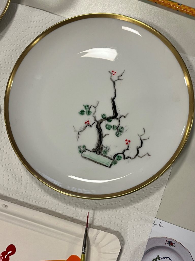 Ergebnis des Workshops Teller mit grünem und pinkem Baumdesign auf weißem Grund und goldenem Rand.